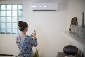 Femme baissant la température de sa climatisation pour faire des économies d'énergies